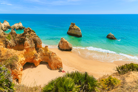 Een strand op Portugal met een blauwe lucht en kristal heldere zee